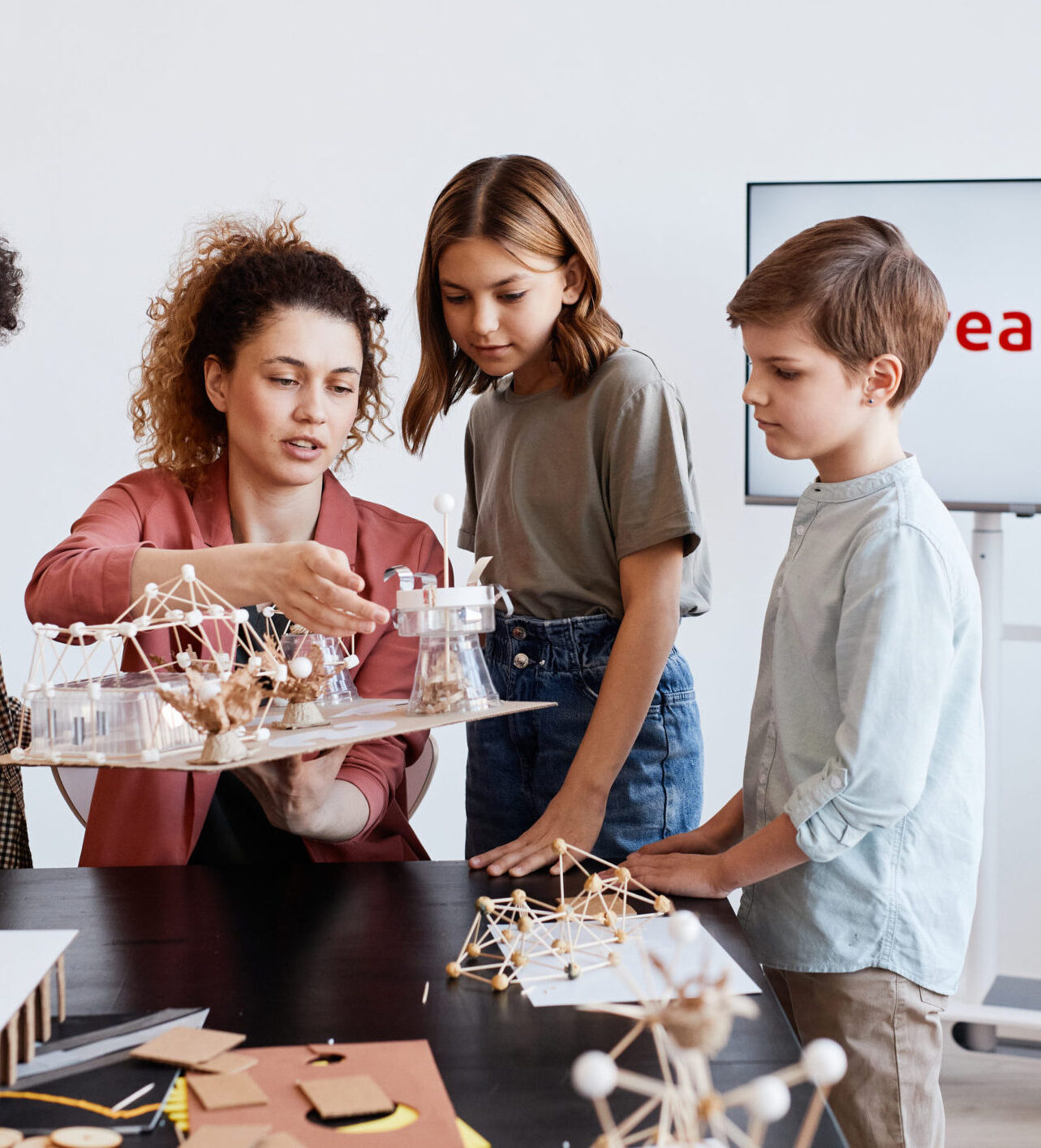Portrait of female teacher helping children making wooden models during art and craft class in school